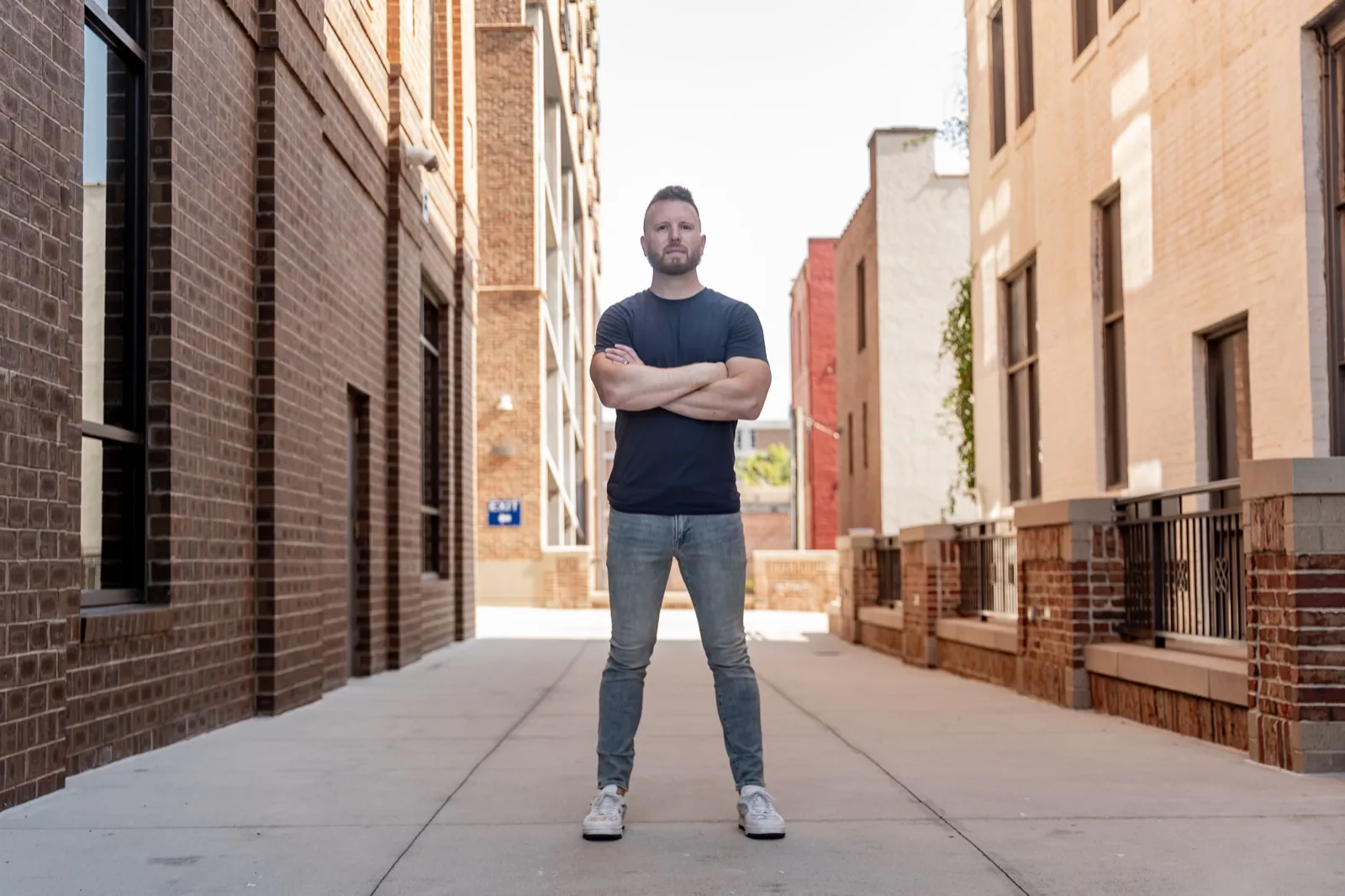 Austin Houser standing in an alley, arms crossed