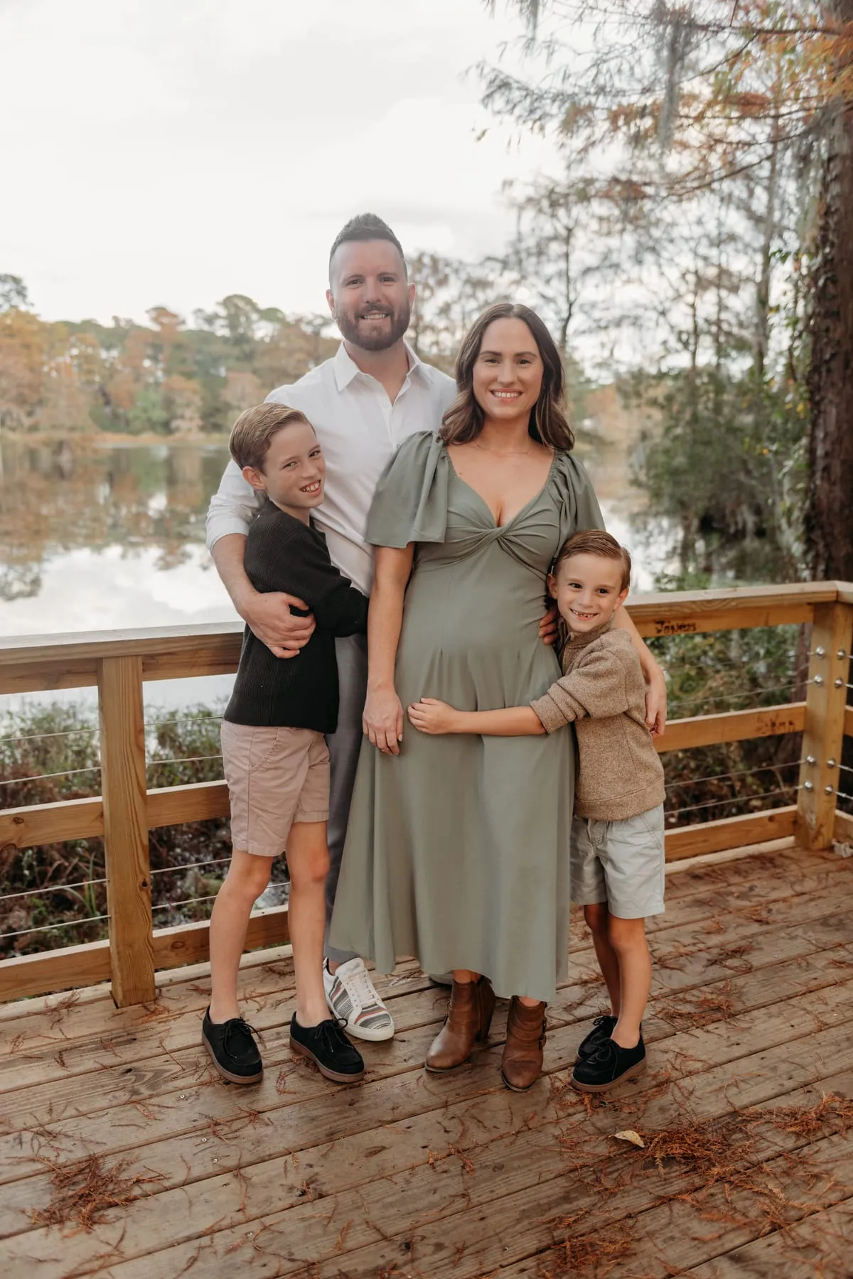 Austin with his wife and two sons on a lakeside dock